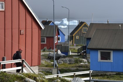 Groenland, cote ouest, Ile de Disko, maisons du village de Qeqertarsuaq et icebergs en arrière plan