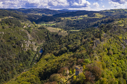 France, Haute Loire, Loire river Valley, Lafarre, the 11th century Tour de Mariac ruins of the Chateau de Lafarre on a volcanic hillock overlooking the gorges of the Loire on the left and its tributary La Langougniole on the right, the Mezenc plateau in the background (aerial view)