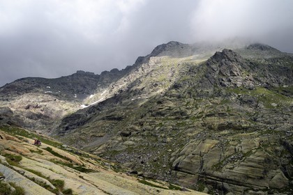 France, Alpes-Maritimes, parc national du Mercantour (Mercantour National Park), the Vallee des Merveilles (Valley of Wonders) scattered with thousands of rupestral engravings of the Bronze Age, hikers gathered around the so called rock of The Sorcerer on the chiappes yellow schist flagstones and Mount Bego in the background