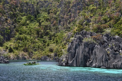 Philippines, Calamian Islands dans le nord de Palawan, Coron Island Natural Biotic Area, pirogue à balancier dans un lagon au pied des falaises de calcaire du Permien d'origine jurassique