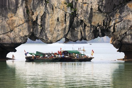 Vietnam, Quang Ninh Province, Halong Bay, listed as World Heritage by UNESCO, fishing boats under a naturel  limestone arch