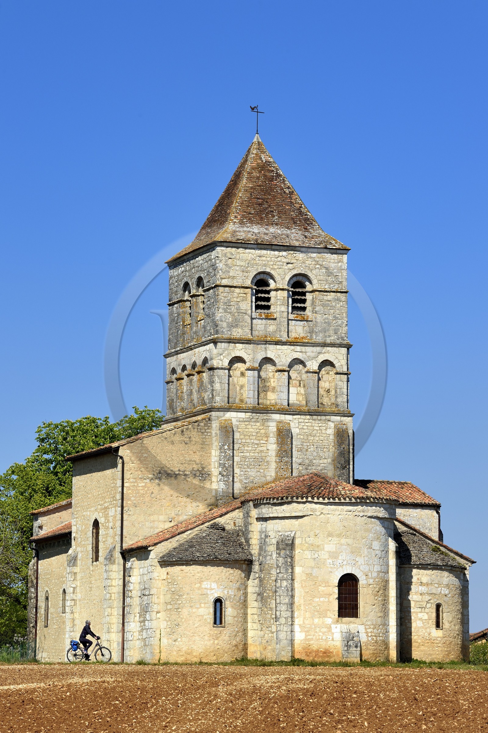 France, Dordogne (24), Périgord Vert, Javerlhac-et-la-Chapelle-Saint-Robert, cycliste faisant la véloroute La Flow Vélo devant le chevet de l'église romane XIIème siècle de La Chapelle-Saint-Robert, église de l'ancien prieuré fondé par un disciple du premier abbé de la Chaise-Dieu Robert de Turlande