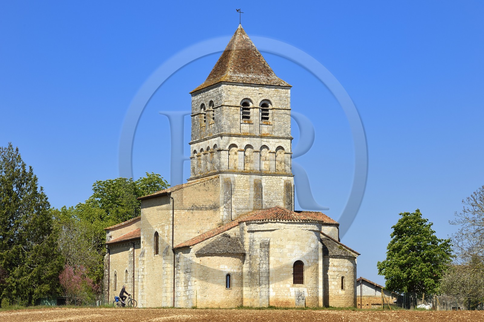 France, Dordogne, Périgord Vert, Javerlhac-et-la-Chapelle-Saint-Robert, cyclist traveling along the Flow Vélo cycle route in front of the 12th century Romanesque church of La Chapelle-Saint-Robert, church of the former priory founded by a disciple of the first abbot of La Chaise-Dieu Robert de Turlande