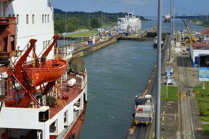 Panama, Colon province, Panama Canal, Gatun locks, mechanical mules or electric locomotives guiding a Panamax container ship between the lock walls