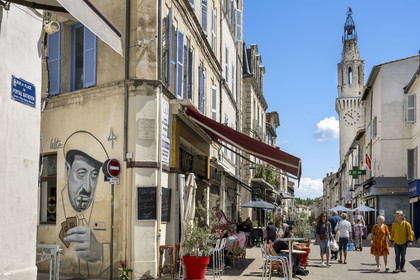 France, Vaucluse, Avignon, on a wall of Mon Bar rue de la Campane, a portrait of Raimu during the card game in the film Marius by Marcel Pagnol by the graffiti artist Lekto, the Augustinian bell tower, the only vestige of the former Augustinian convent in the background