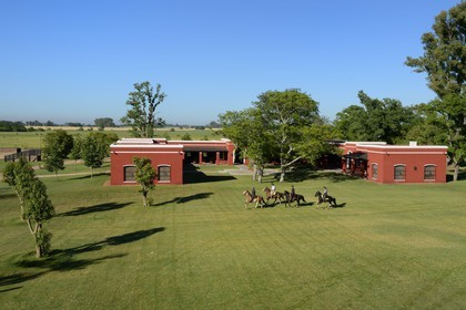 Argentine, province de Buenos Aires, San Antonio de Areco, estancia La Bamba de Areco, gauchos à cheval passant devant l'étable des chevaux utilisés pour le polo