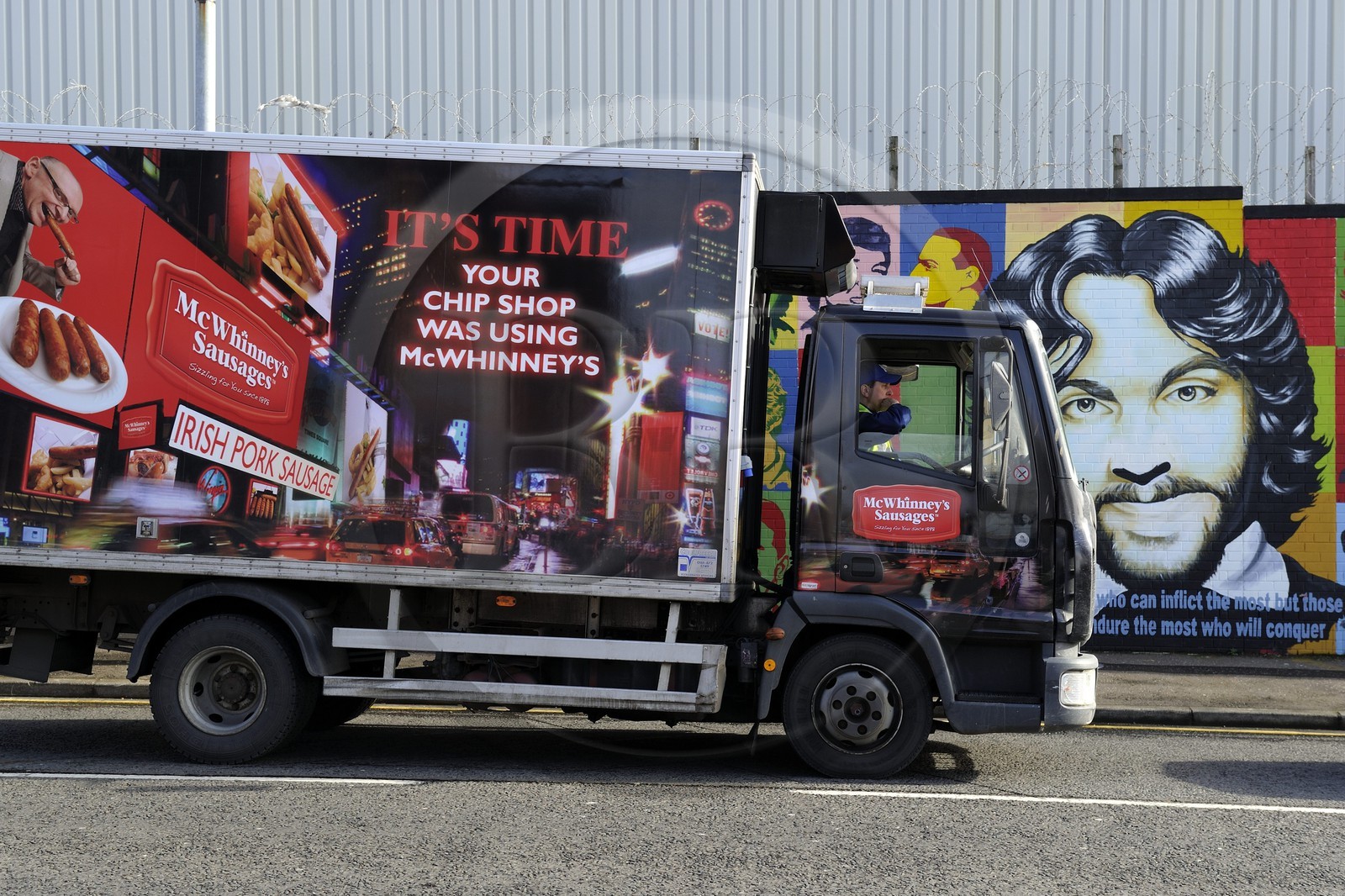 Royaume-Uni, Irlande du Nord, Belfast Ouest, le quartier catholique de Falls, International ou Solidarity Wall, peintures murales politiques sur Falls Road et fresque publicitaire pour des saucisses sur un camion de livraison