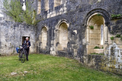 France, Dordogne, Perigord Vert, Villars, cyclist riding the Flow Vélo in the ruins of the Cistercian Abbey of Boschaud from the 12th century that belonged to the Abbey of Clairvaux