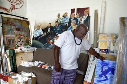 France, Paris, Barthelemy Toguo, the artist founder of Bandjoun Station in Cameroon (shown in the painting in the background), in his Parisian studio