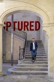 France, Vaucluse, Avignon, Collection Lambert, Museum of Contemporary Art, housed in the 18th century private mansions of Caumont and Montfaucon, Stéphane Ibars, artistic director of the Collection, descends the stairs under Ruptured (1970) by the artist Lawrence Weiner