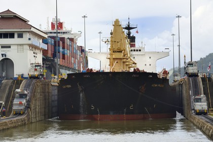 Panama, Panama Canal, Miraflores locks, mechanical mules or electric locomotives guiding a Panamax cargo between the lock walls