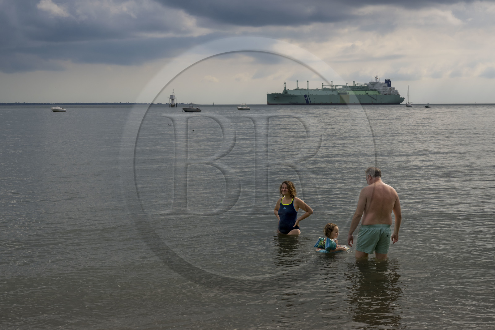 France, Loire-Atlantique (44), Estuaire de la Loire, Saint-Nazaire, plage de Trébézy, bain de mer familial et cargo passant au large en arrière plan