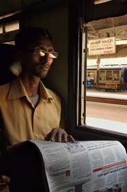 Sri Lanka, Colombo, Colombo Fort train station, passenger reading a newspaper