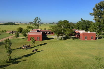 Argentine, province de Buenos Aires, San Antonio de Areco, estancia La Bamba de Areco, gauchos à cheval passant devant l'étable des chevaux utilisés pour le polo