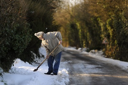 France, Manche, Cotentin, Sainte Marie du Mont, man removing snow in front of his home
