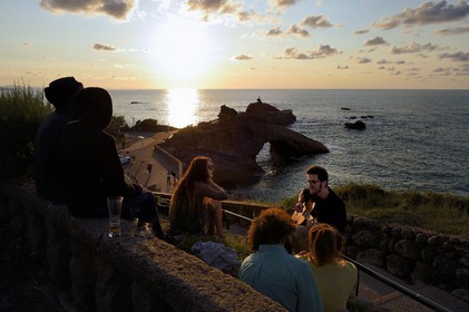France, Pyrenees Atlantiques, Basque Country, Biarritz, young people playing guitar on sunset, the Rocher de la Vierge (Virgin rock) in the background