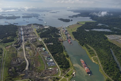 Panama, Colon province, Panama Canal, Panamax cargo passing the Gatun locks, the construction of the new locks on the left and the Gatun Lake in the background (aerial view)