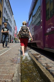 Allemagne, Bade-Wurtemberg, Fribourg en Brisgau, retour d'ecole dans la Kaiser-Joseph Strasse, un des Bächle qui sont des petits caniveaux ouverts qui bordent les trottoirs de la vieille ville