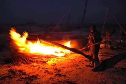 Tanzania, Zanzibar Archipelago, Unguja island (Zanzibar), southeast coast, Bwejuu, ffishermen burning seaweed on a dhow (traditional Arab sailing vessel)
