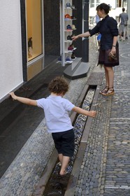 Allemagne, Bade-Wurtemberg, Fribourg en Brisgau, enfant jouant dans un des Bächle qui sont des petits caniveaux ouverts qui bordent les trottoirs